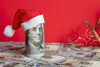 A rolled-up $100 bill with a small Santa hat on top