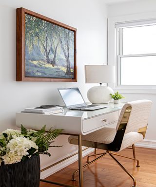 Neutral office space with framed tree artwork hanging above a white desk