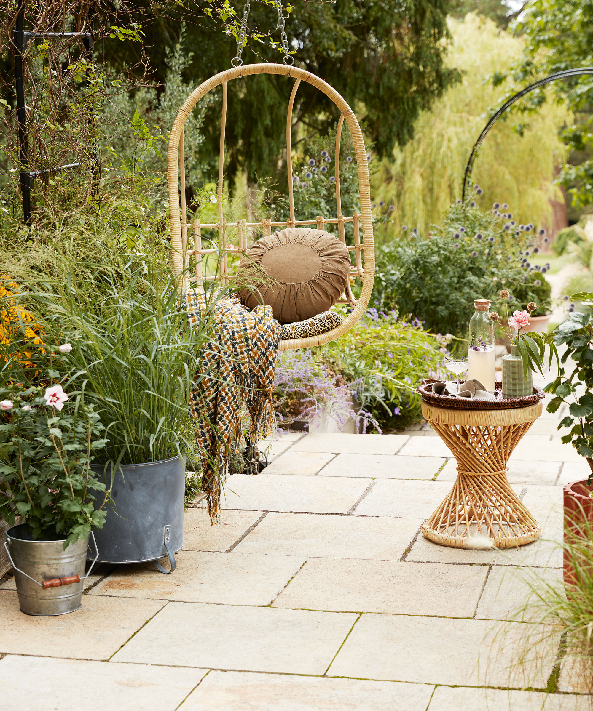 garden patio with hanging chair surrounded by potted plants