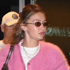 Gigi Hadid arrives at airport wearing a pink cardigan, white T-shirt, faded jeans, brown loafers and white socks