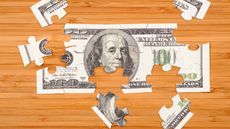 Puzzle of a hundred-dollar bill on a wooden background.