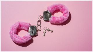 Pink locked handcuffs for adult games on pink background