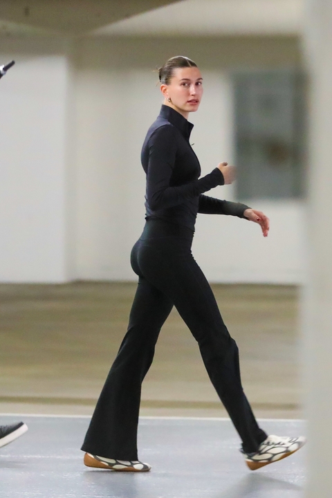 Hailey Bieber walking in Los Angeles wearing a black zip up jacket and two tone sneakers