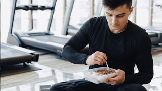 A man bulking, eating a meal in the gym