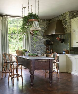 A deep green kitchen covered in a nature inspired wallpaper