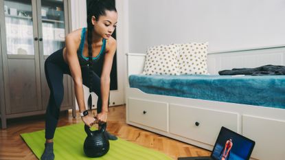 Woman works out with a kettlebell in her bedroom