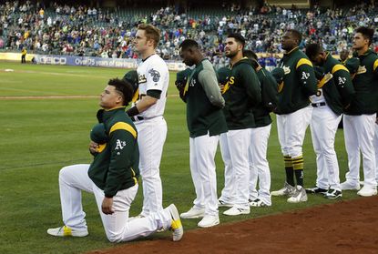 Oakland Athletics catcher Bruce Maxwell kneels during the national anthem before the start of a baseball game against the Texas Rangers Saturday, Sept. 23, 2017, in Oakland, Calif. 