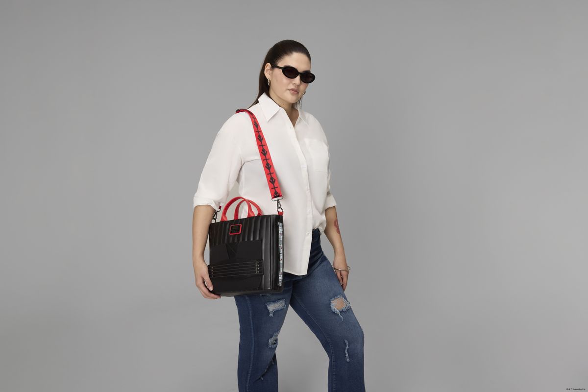 A woman holds the Loungefly Darth Maul bag in a gray environment