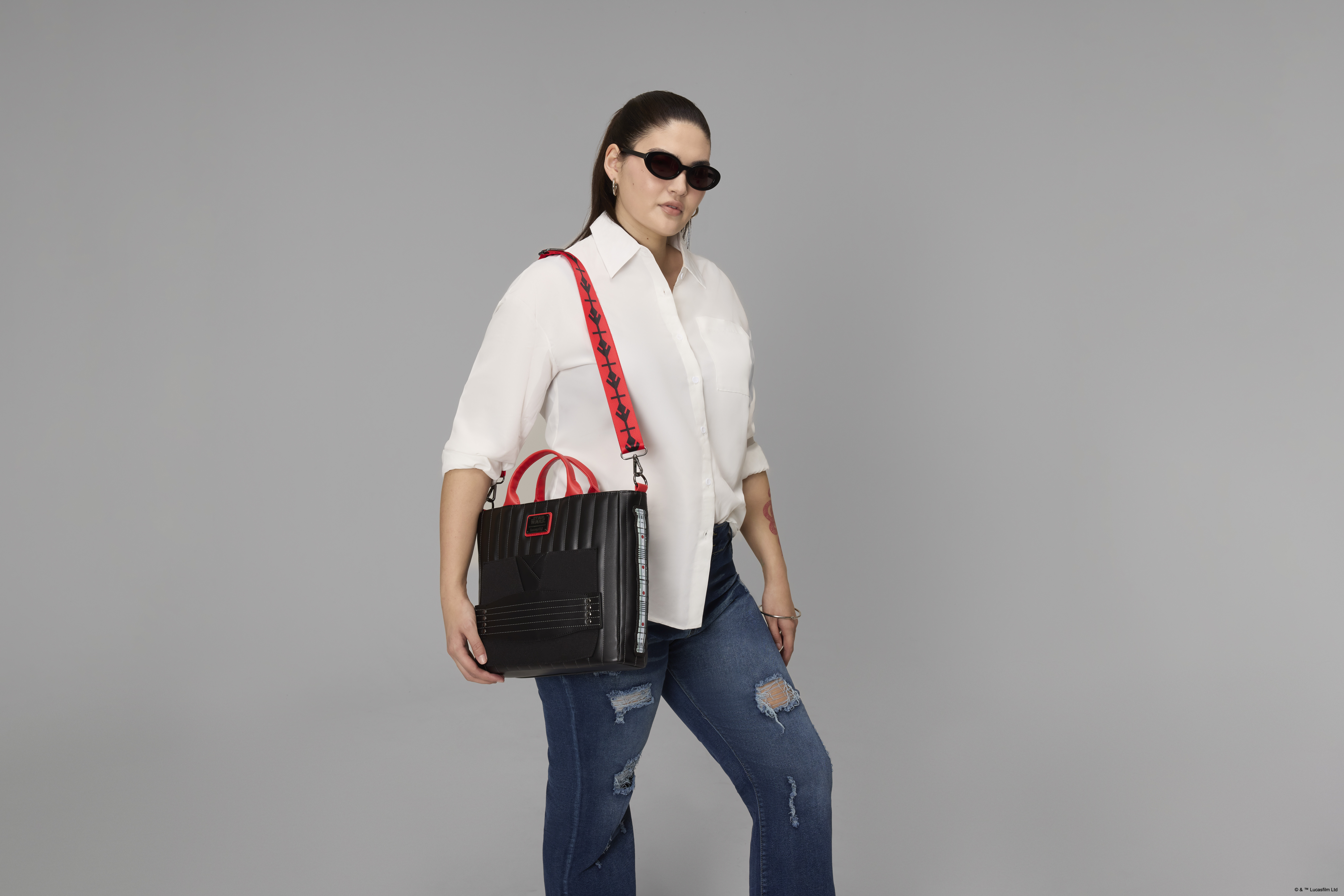 A woman holds the Loungefly Darth Maul bag in a gray environment