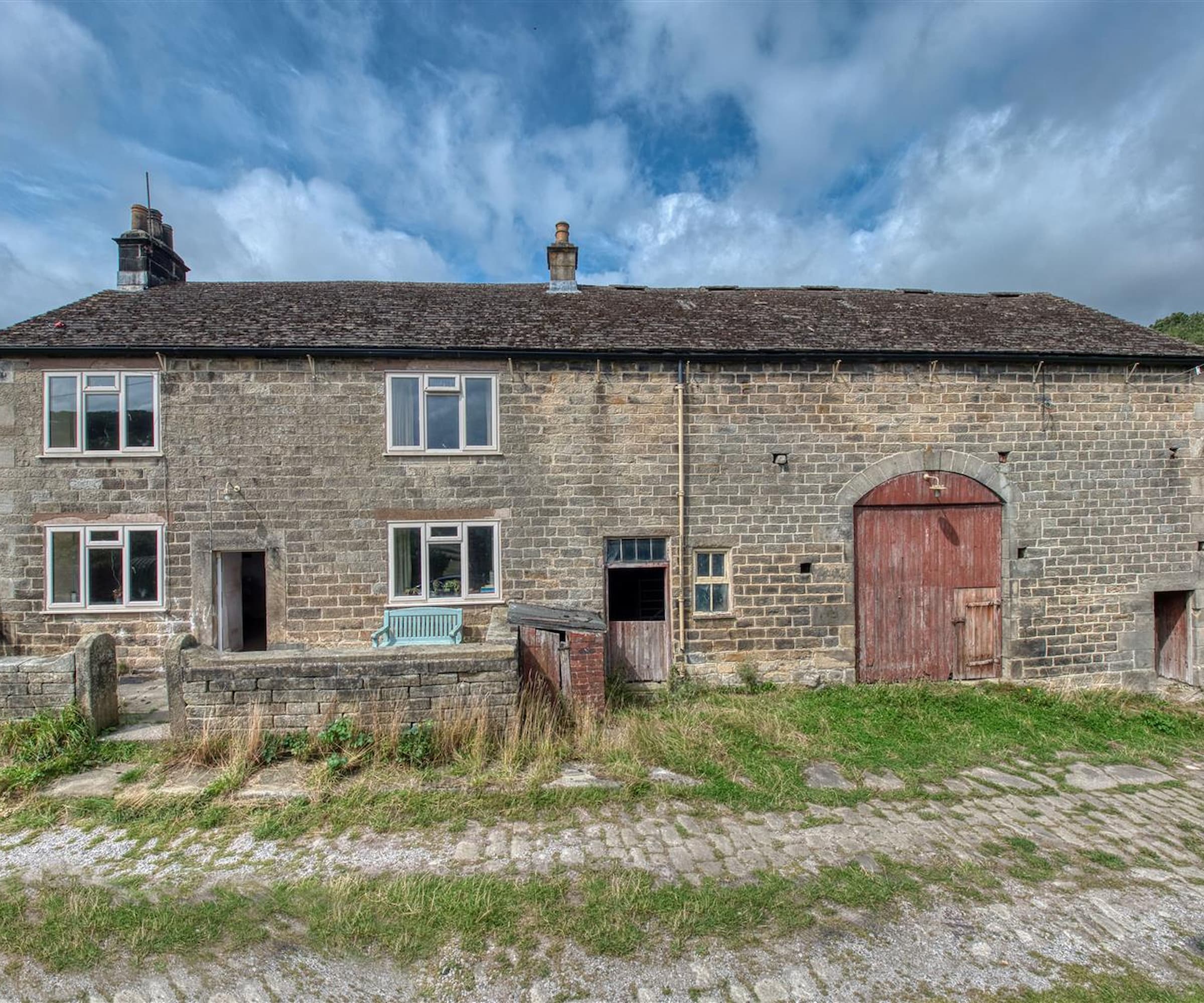 A stone farmhouse with wooden barn door and a stone front wall and stone garden