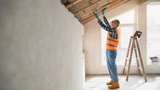 man putting insulation in between battens