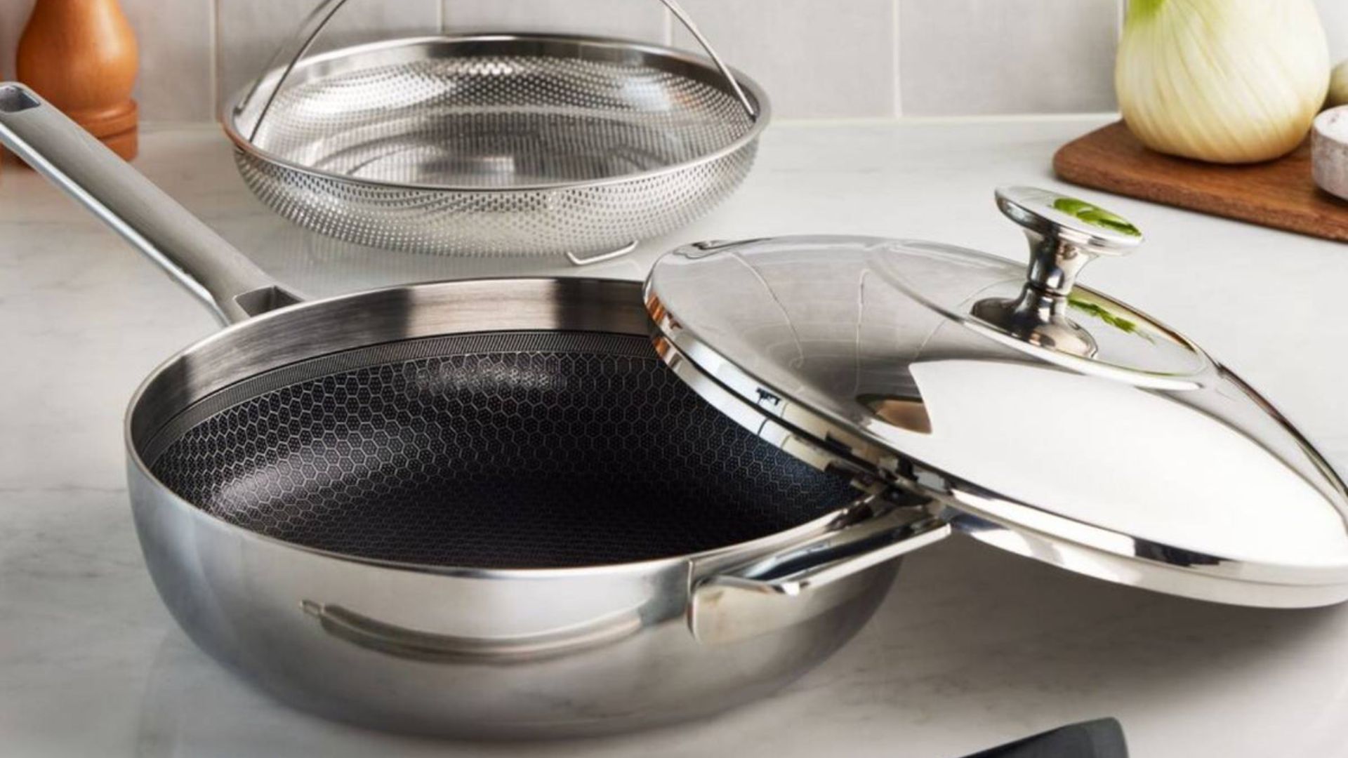 Lakeland 10-in-1 Tri-Ply Only Pan Pro on a counter with the steamer and spatula in front at the lid propped on top