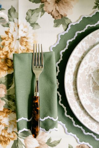 fall table with green napkins and placemat, splatterware plates and floral tablecloth