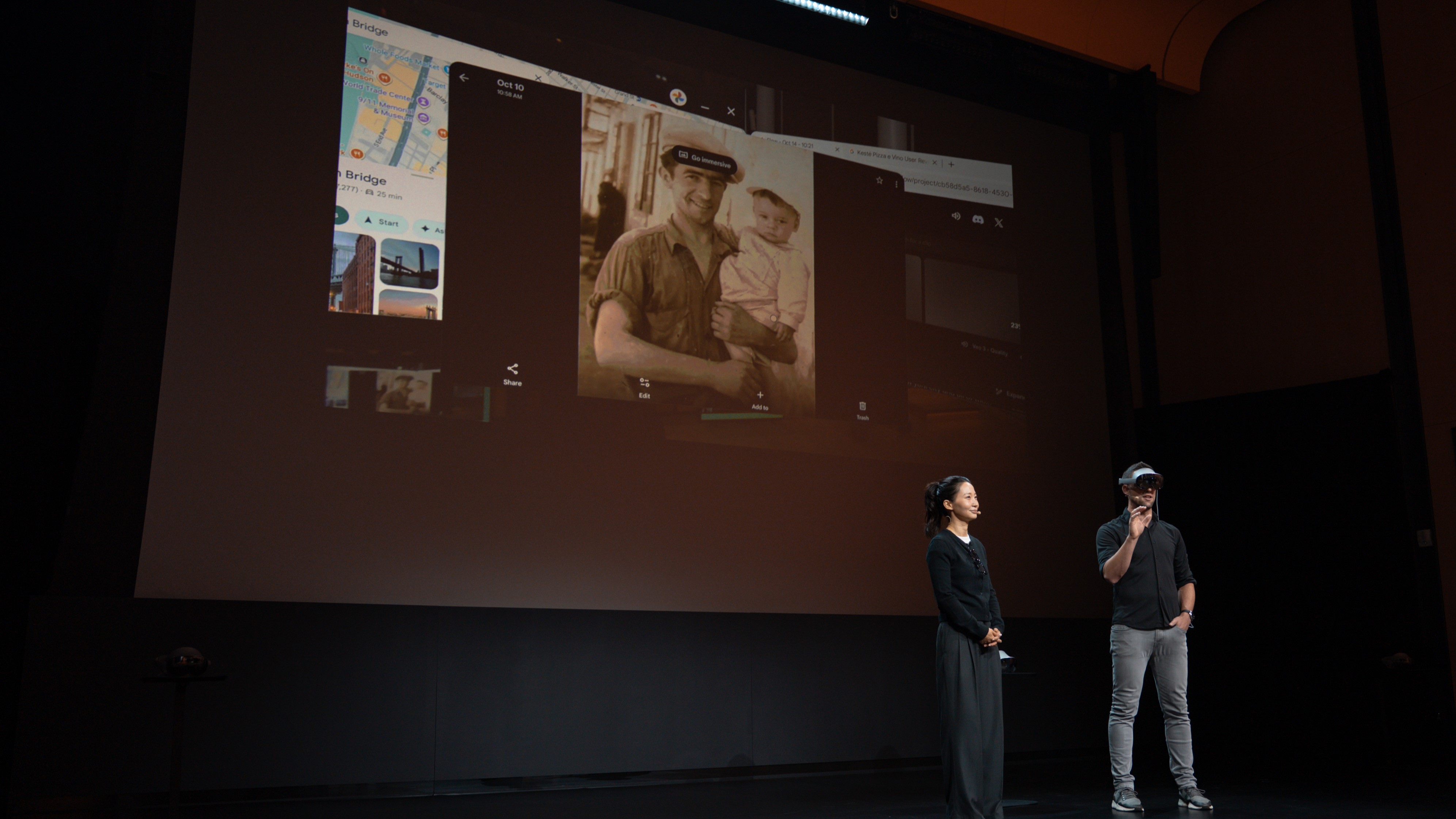 Photo of Samsung&#039;s Jin Park and Max Spear standing on stage, Spear wearing the Samsung Galaxy XR headset, with a Google Photos demo on a screen behind them.