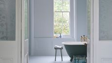 light and airy bathroom with pale blue walls, window and roll-top bath