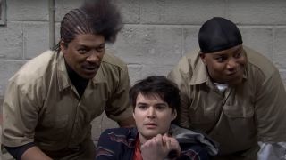 Eddie Murphy and Kenan Thompson flank a seated and scared Michael Longfellow in SNL50's "Scared Straight" sketch.