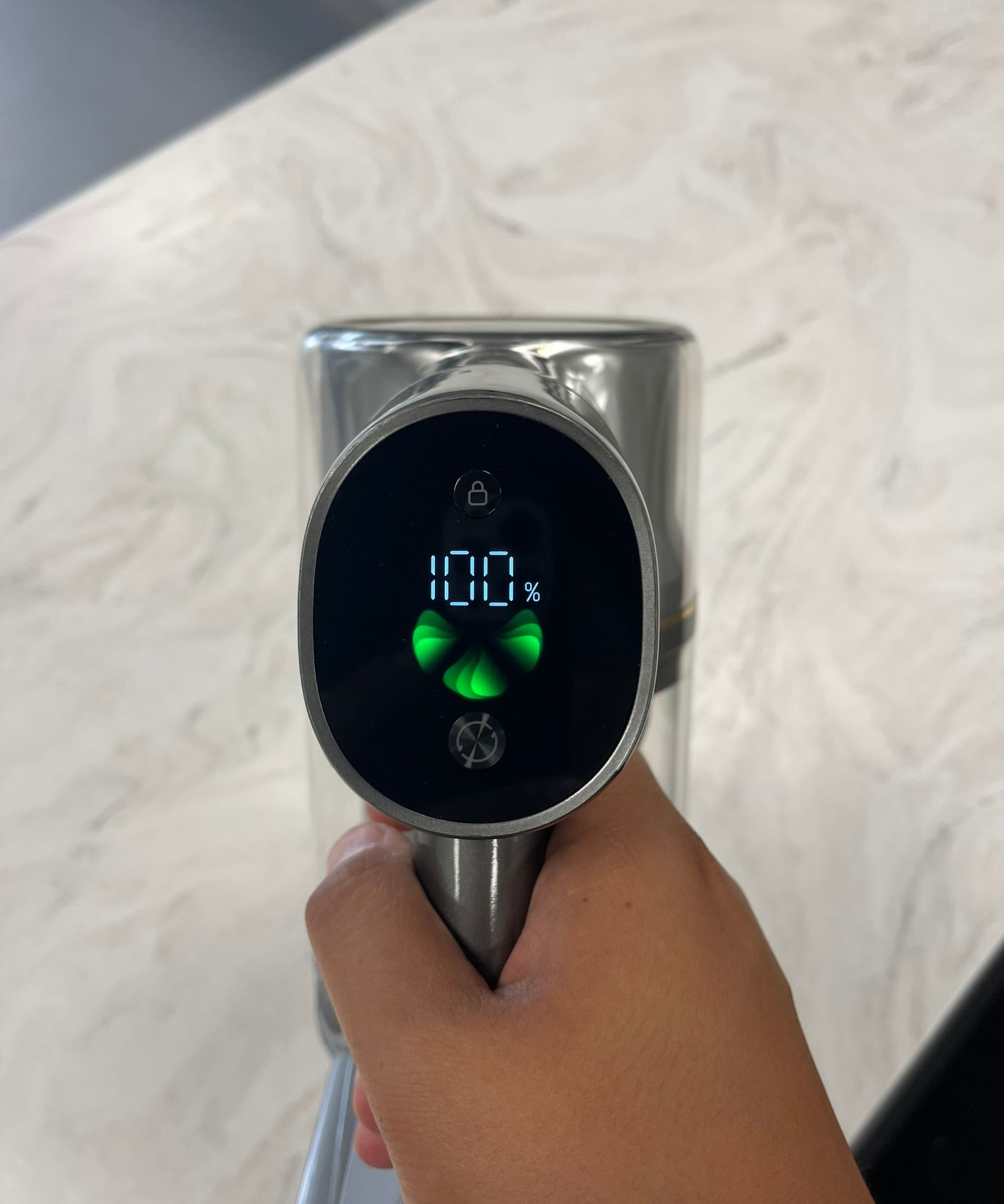 Hand holding the Dreame R20, showing the vacuum's screen displaying 100% battery life in Future test center