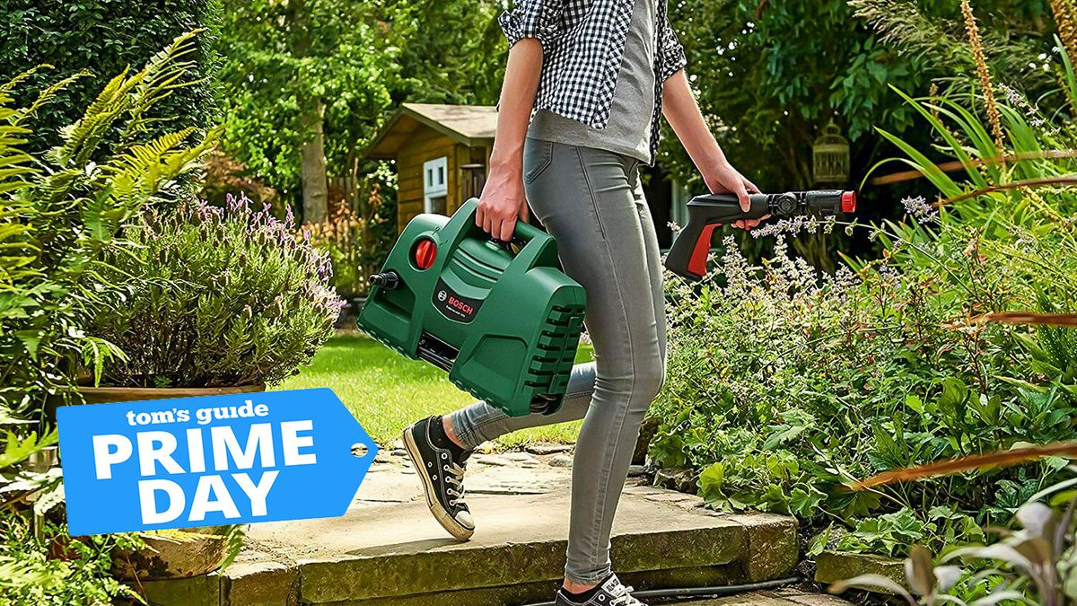 A woman holding a Bosch EasyAquatak 100 pressure washer and walking through a garden