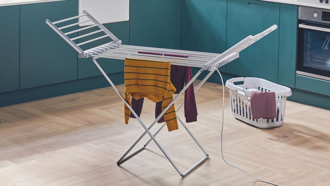 Winged heated airer in a kitchen with blue cabinets and wooden flooring