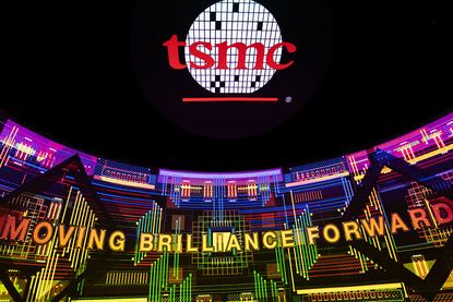 The TSMC logo appears on a large corporate display with the slogan MOVING BRILLIANCE FORWARD