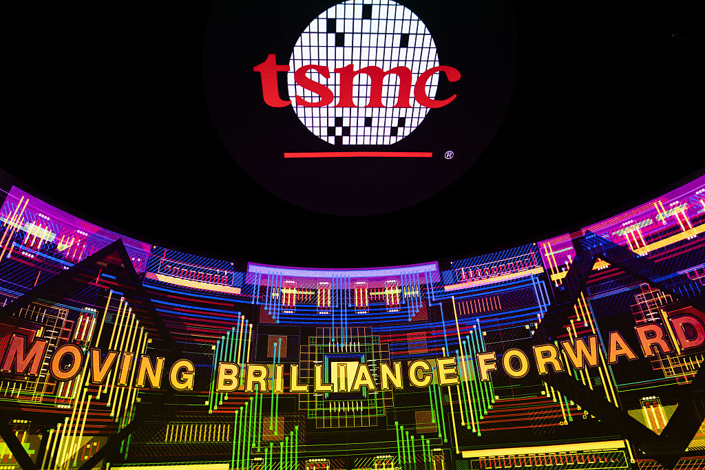 The TSMC logo appears on a large corporate display with the slogan MOVING BRILLIANCE FORWARD