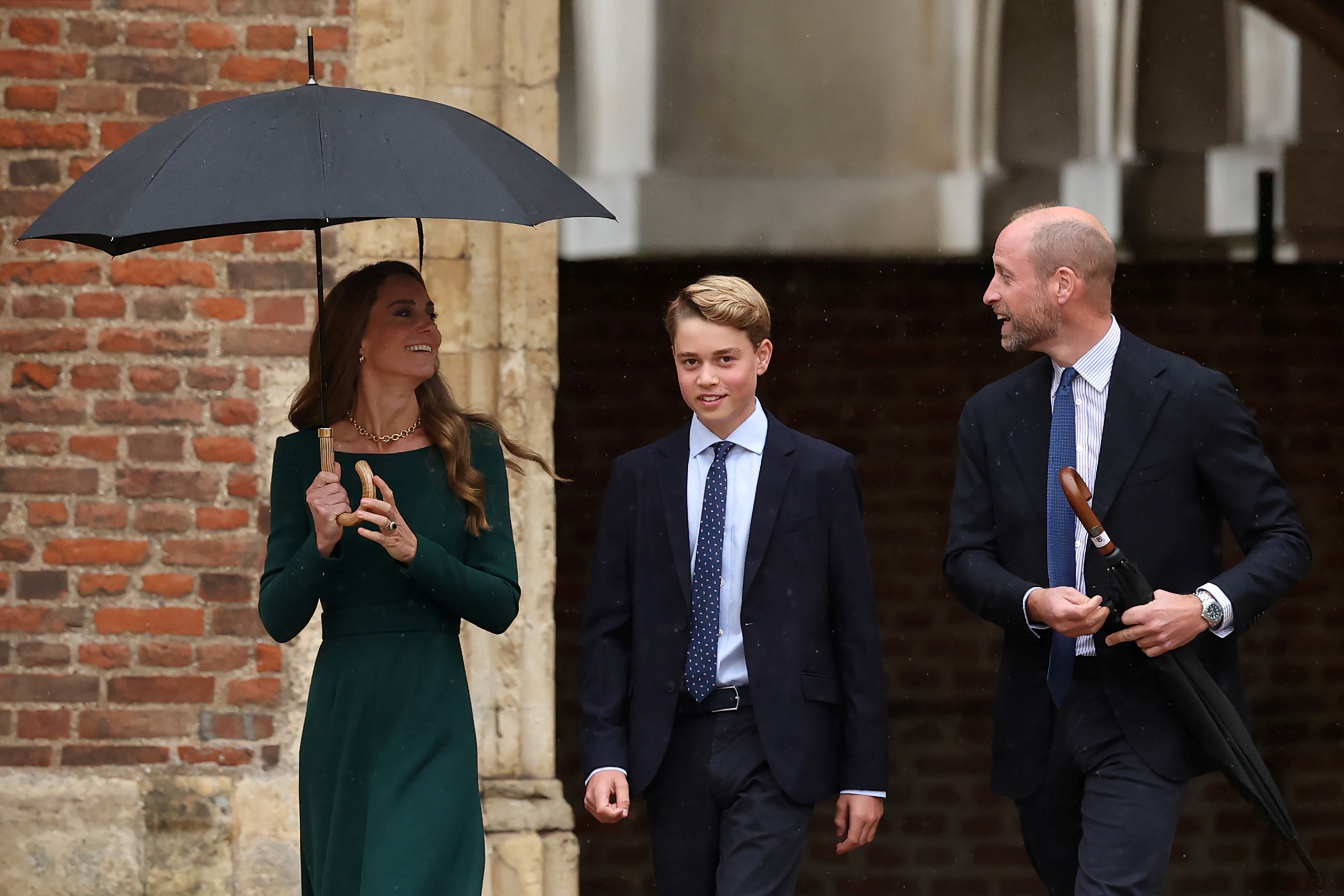 Princess Kate carrying an umbrella walking next to Prince George and Prince William