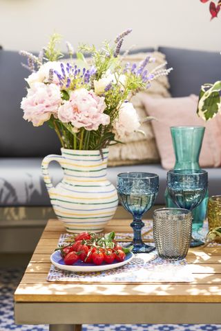 vase of flowers and glasses on table outside entertaining