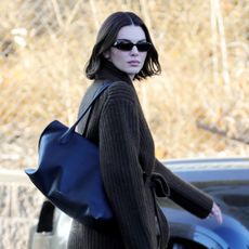 Kendall Jenner wearing a sweater and black The Row tote bag with black leggings and Ugg boots