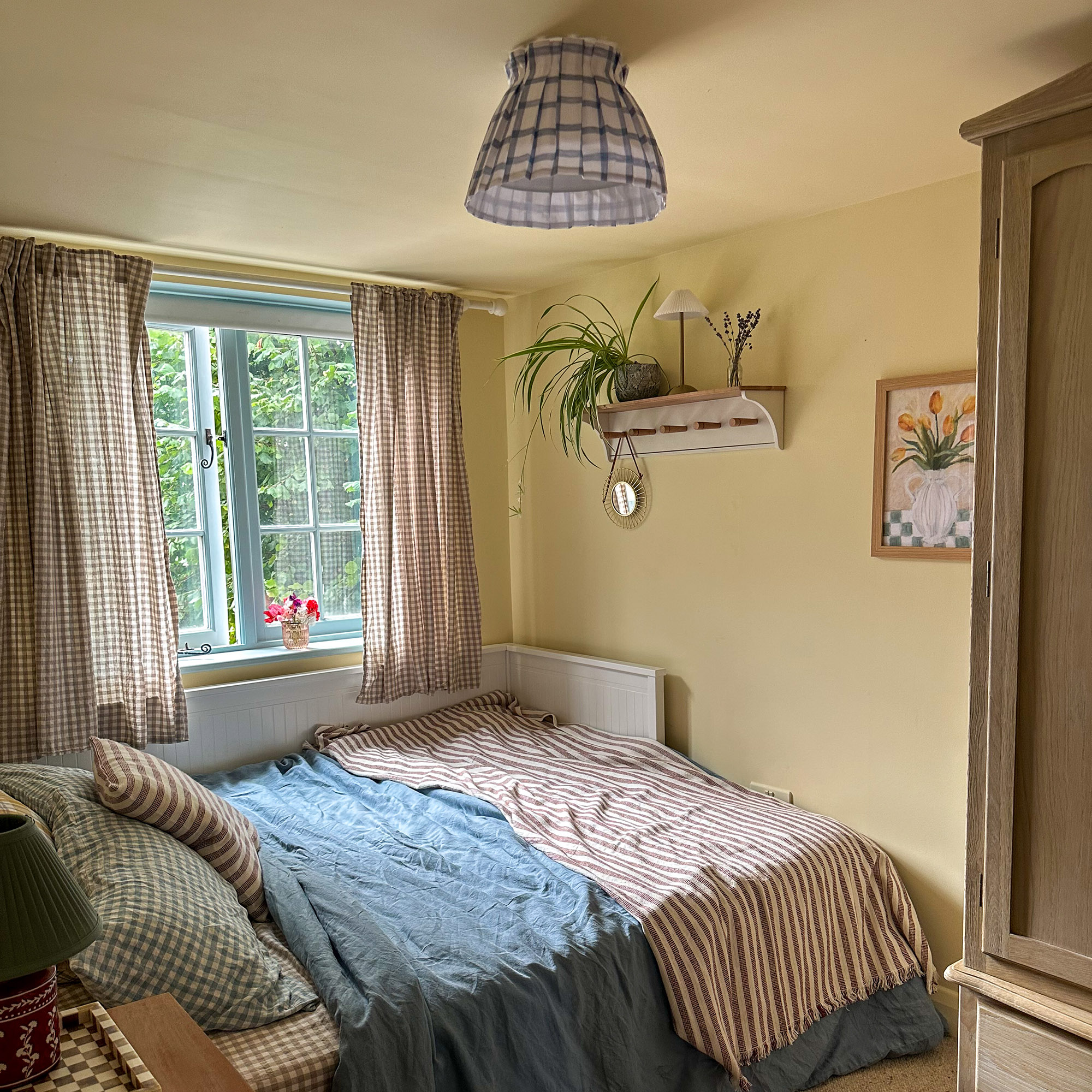 yellow bedroom with bed covered in striped and check sheets and pillows