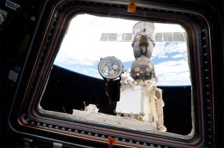 A Breitling wrist chronograph is seen floating in front of a window on board the International Space Station.