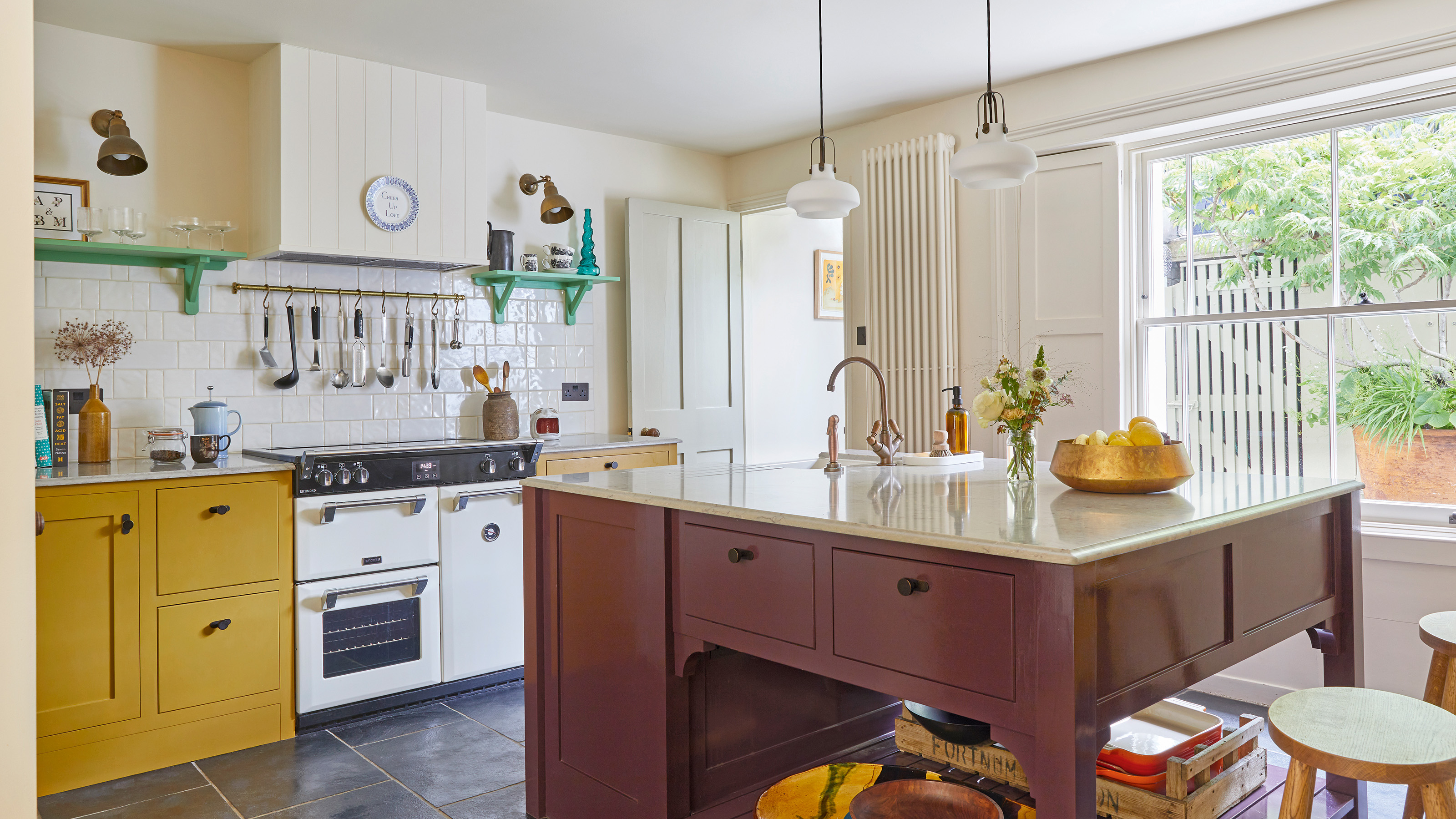 kitchen with yellow cabinetry and white range cooker style over, green open shelves and plum-coloured island 