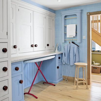 laundry room with white cupboards and wooden flooring