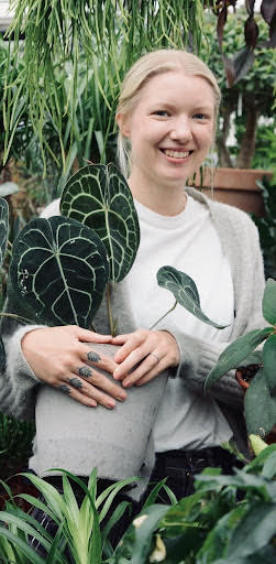 Woman in white top holding large plant 