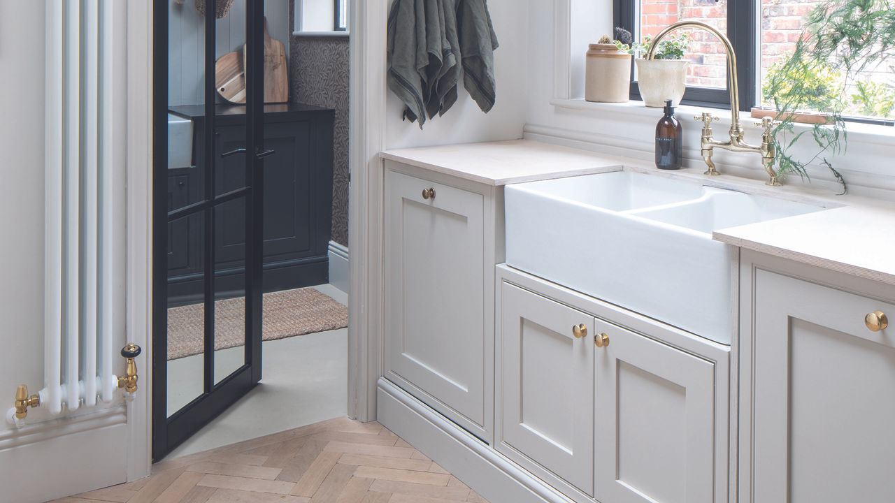 Grey shaker kitchen with gold cup handles and black crittall door leading to utility room.