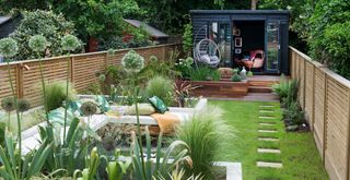 Garden with clearly defined zones with seating areas and a summer house painted black