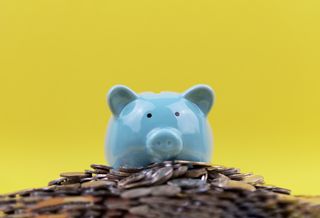 blue piggy bank with coins and a yellow background