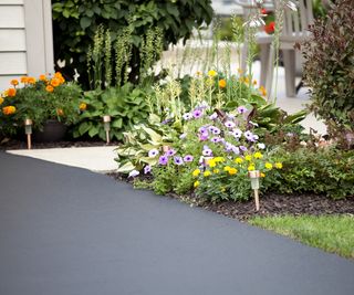 Driveway and frontyard entryway with flowers and solar lights lining the edge