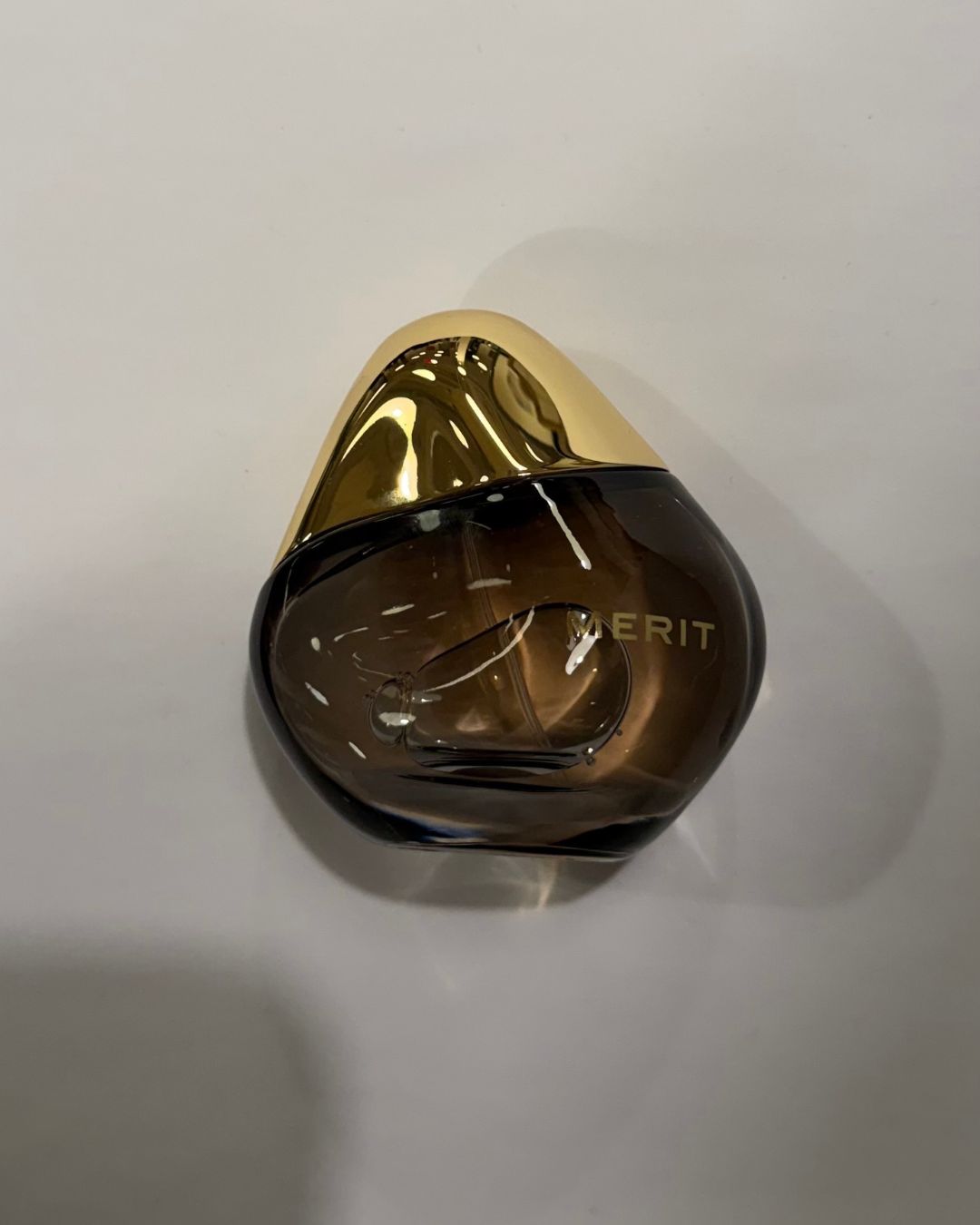 A bottle of Merit Retrospect L'Extrait de Parfum.