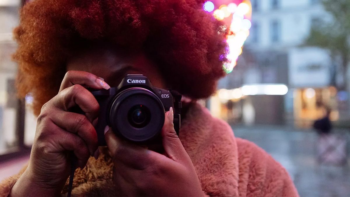 A photographer using the Canon EOS R50 in a street setting