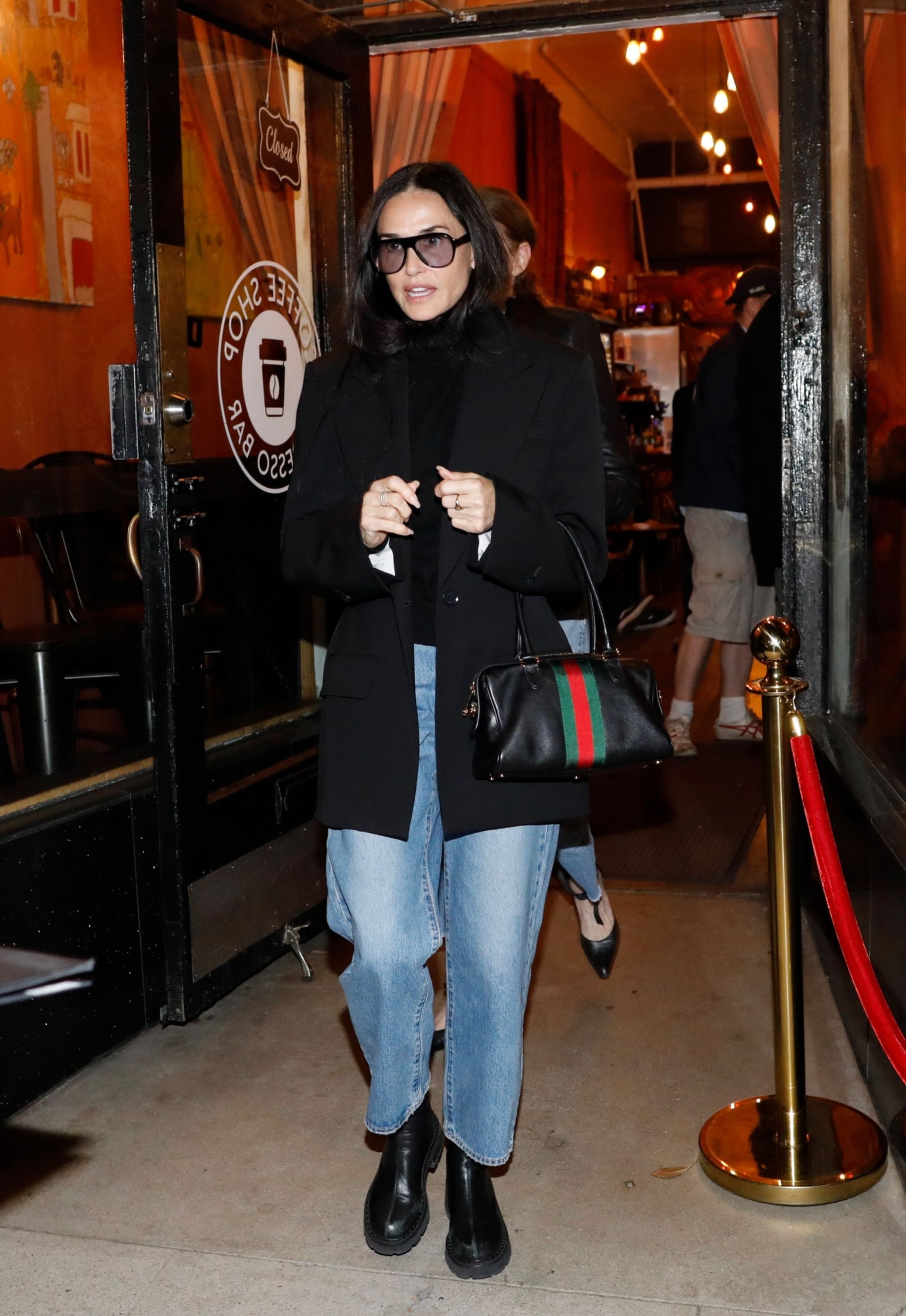 Demi moore wears jeans, boots, and a black jacket with the black gucci borsetto bag.