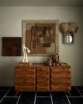 a wood sideboard with maximalist neutral decor on the walls