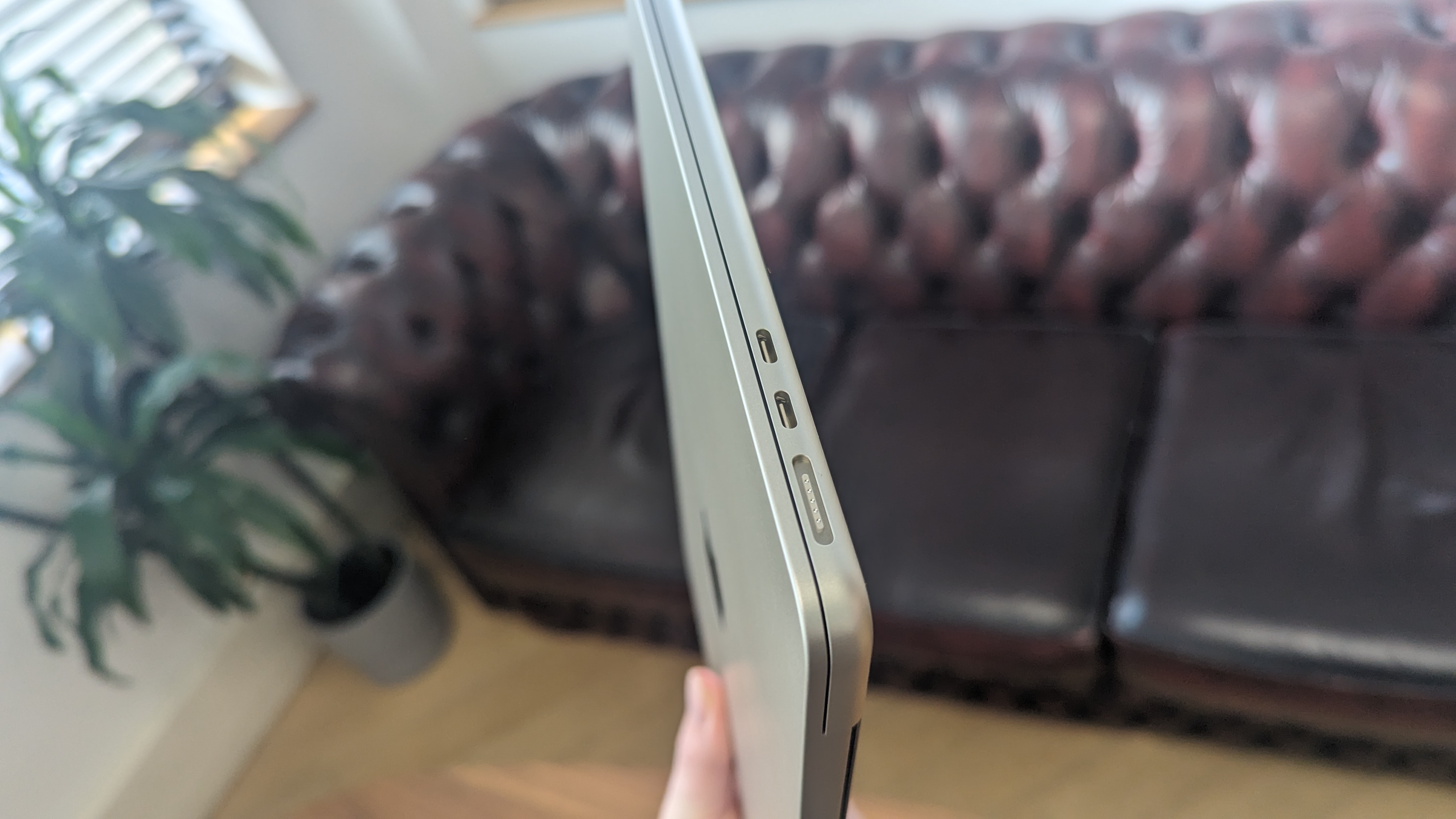 Den nye MacBook Air bliver holdt foran en sofa.