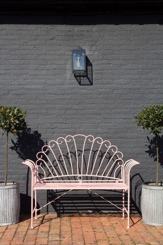painted pink bench against a black painted wall