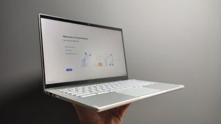 Billig laptop: En hånd holder en åpen Acer Chromebook Spin 514 mot en hvit vegg