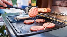 Flipping burgers on a griddle attachment on a grill