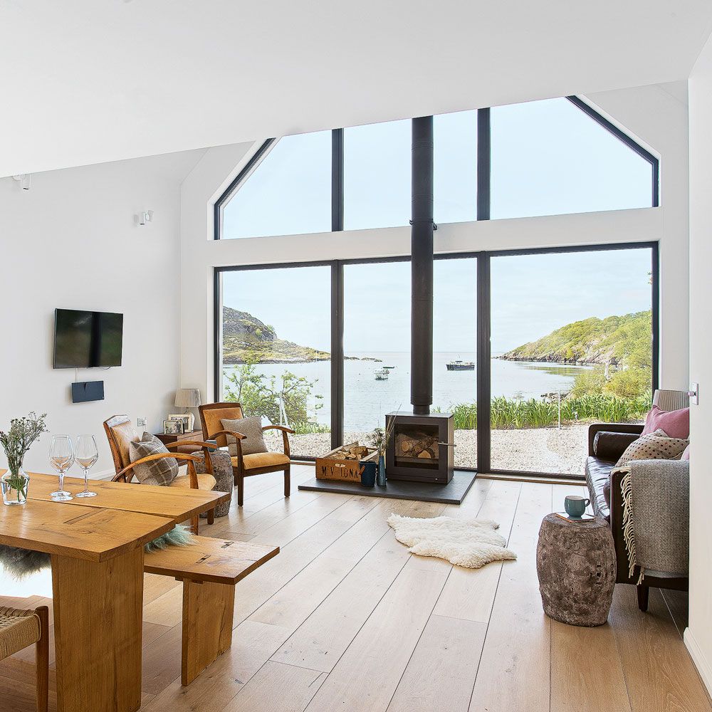 living room with white wall fire place at glass window and wooden flooring