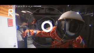 Observation screenshot of an astronaut in an orange spacesuit in the interior of a spacecraft