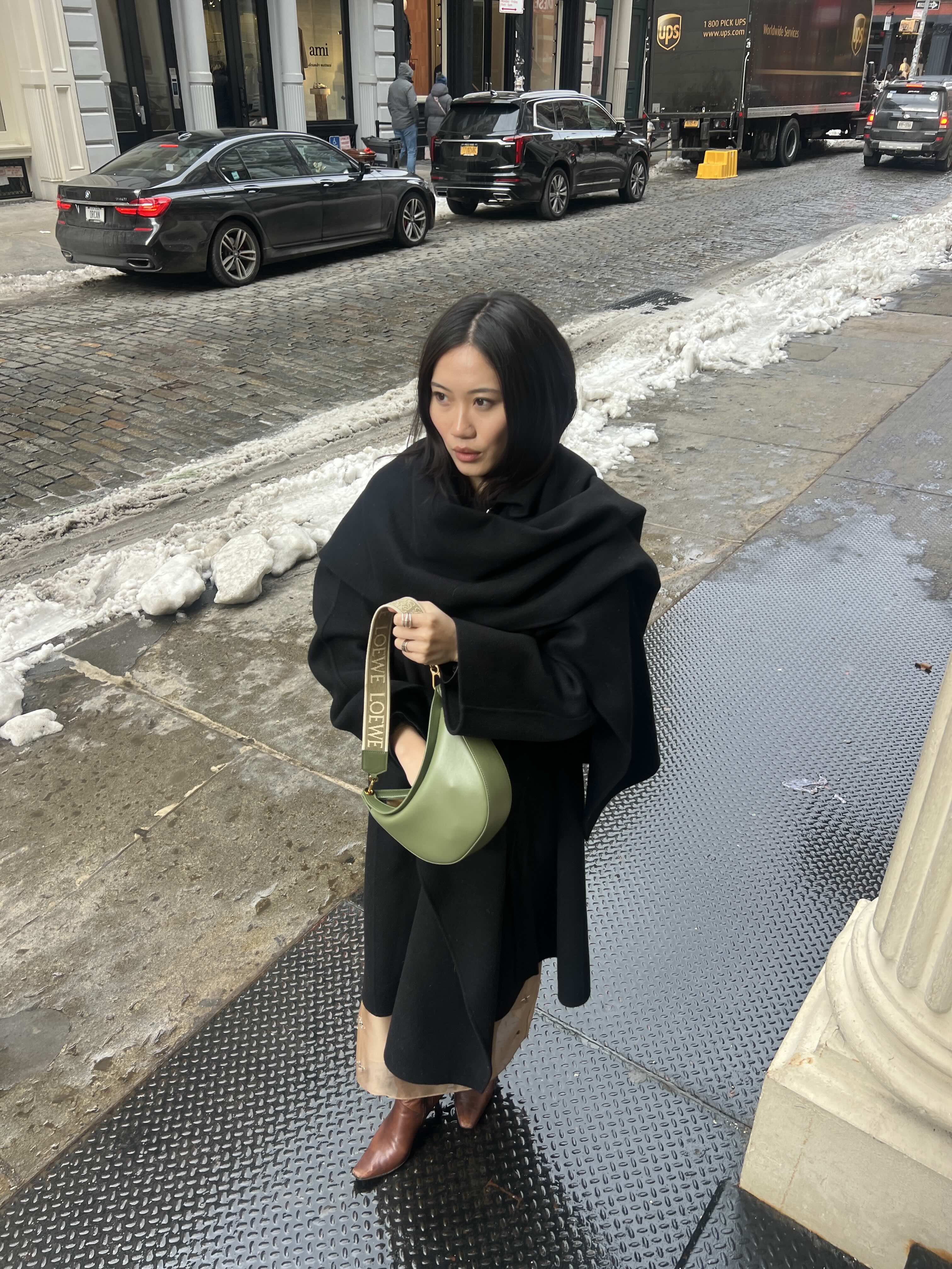 Vivian Li holding a green Loewe bag while wearing a black coat
