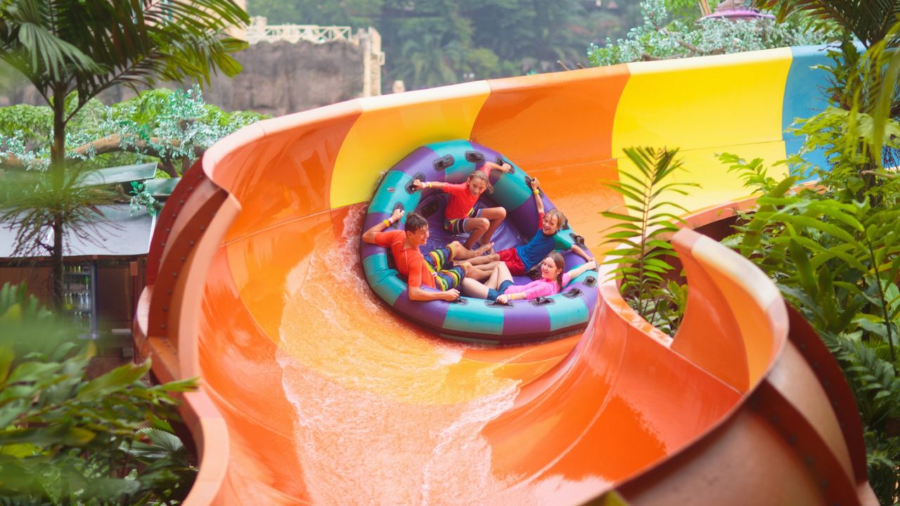 Four young people take a ride on a colorful raft down a water slide