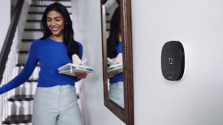 ecobee SmartThermostat on a wall in front of person walking down stairs